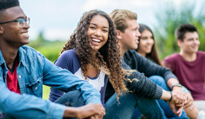 A group of young adults sitting outside
