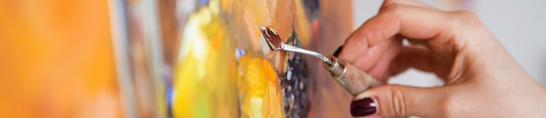 close up working on an oil painting with a pallet knife