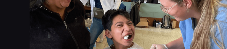 Child with gauze in their mouth smiling at the healthcare professional helping them