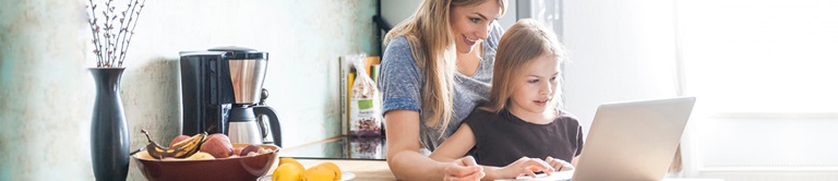 mom and daughter typing on a laptop from home