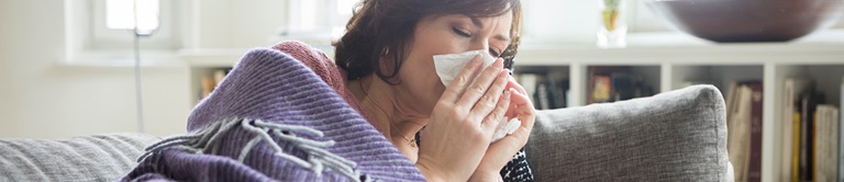woman sick at home using a kleenex