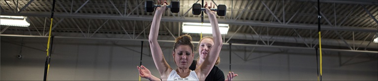 woman lifting weights with a trainer