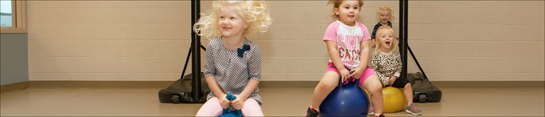 group of kids bouncing on balls in a gym